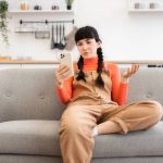 Girl sitting on a couch, looking at her phone.